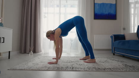 young-woman-is-practising-yoga-at-home-relaxing-in-simple-body-position-sitting-on-floor-with-beautiful-furniture-around.-slim-woman-in-sportswear-standing-on-knees-bending-back-and-doing-camel-pose